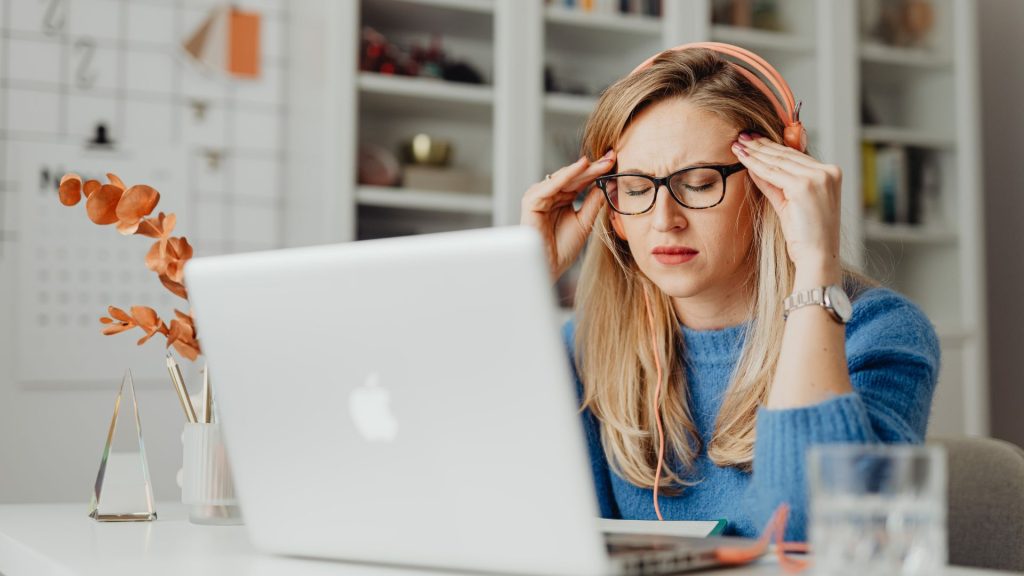 Femme au travail ressentant une fatigue auditive en open space après une écoute prolongée au casque